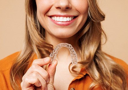 Patient smiling while holding clear aligner