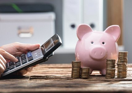 Hands operate calculator near piggy bank