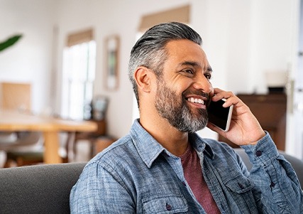Man smiling while talking on phone at home