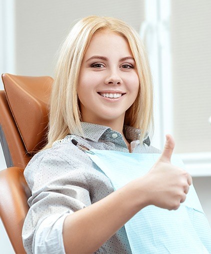 Woman in dental chair giving thumbs up