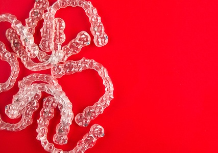 several clear aligners on red background