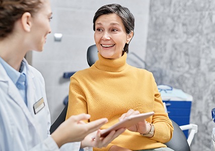 An older smiling woman talking to her dentist