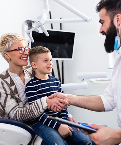 Woman with young son shaking dentist’s hand