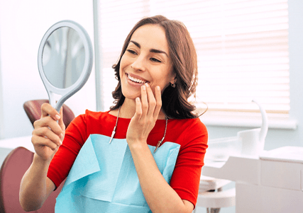 Woman at dentist’s office checking smile in mirror