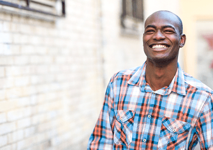 Man in patterned shirt walking past a brick building