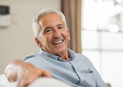 Senior man sitting on couch and smiling