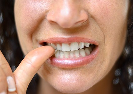 Close-up of woman biting her thumbnail