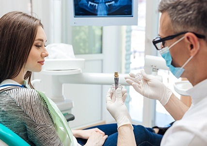 Dentist showing patient a dnetal implant model
