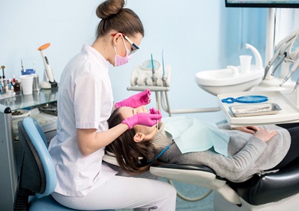 A female dentist performing dental work on a female patient who is lying down in the dentist’s chair