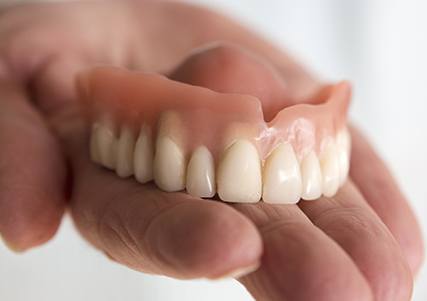 Hand holding full denture