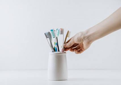Hand reaches for toothbrush in holder