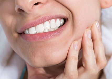 Grimacing woman holding jaw