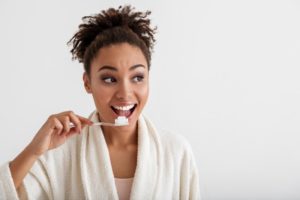 Woman brushing her teeth looking away from camera