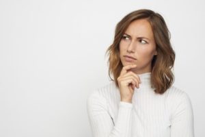 Woman in a white turtleneck thinking