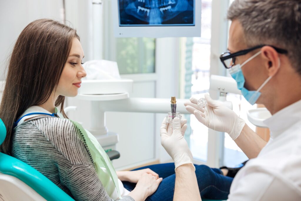 Dentist showing sample implant to patient in chair