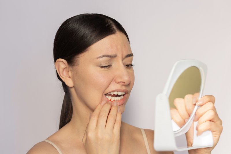 Woman looking at her receding gums in a mirror